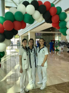 Three nurses posing under a balloon arch in Abu Dhabi